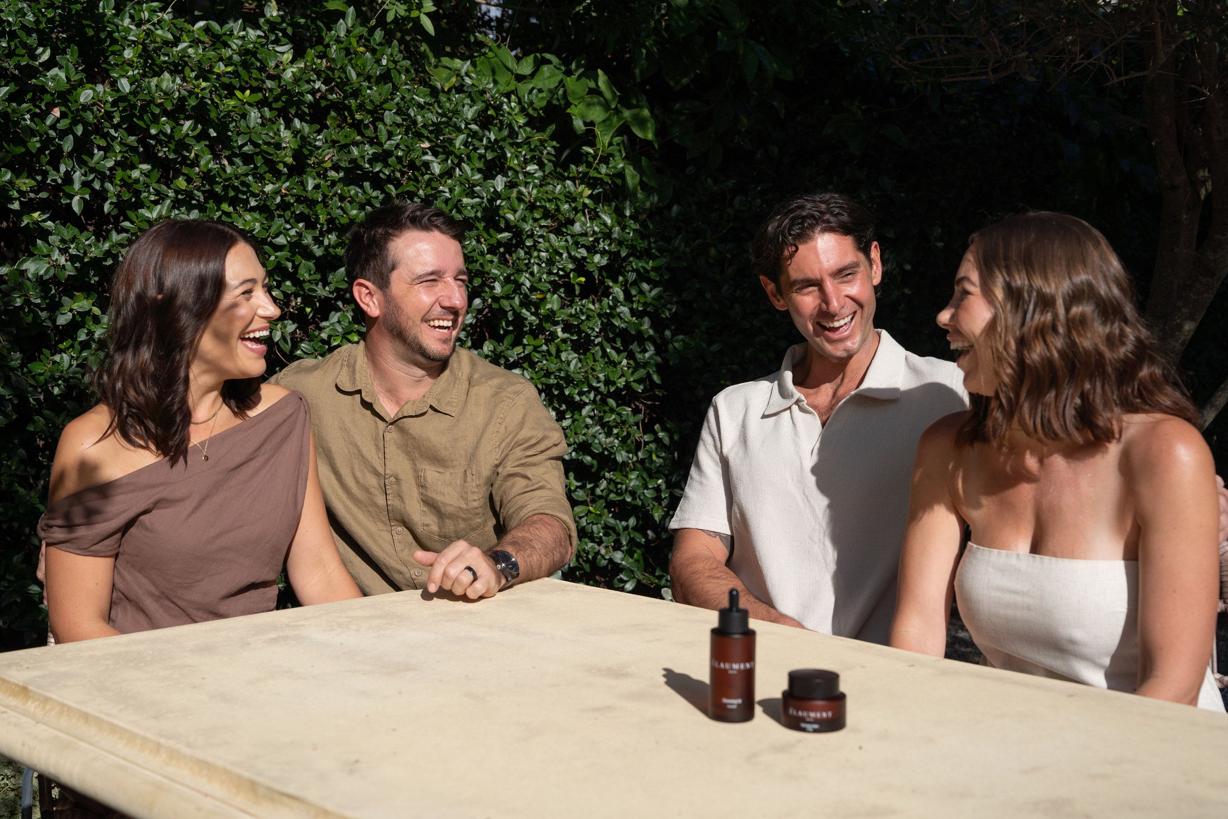 The four Élaument Skin founders at an outdoor table with the Cleansing Oil and Hydration Balm